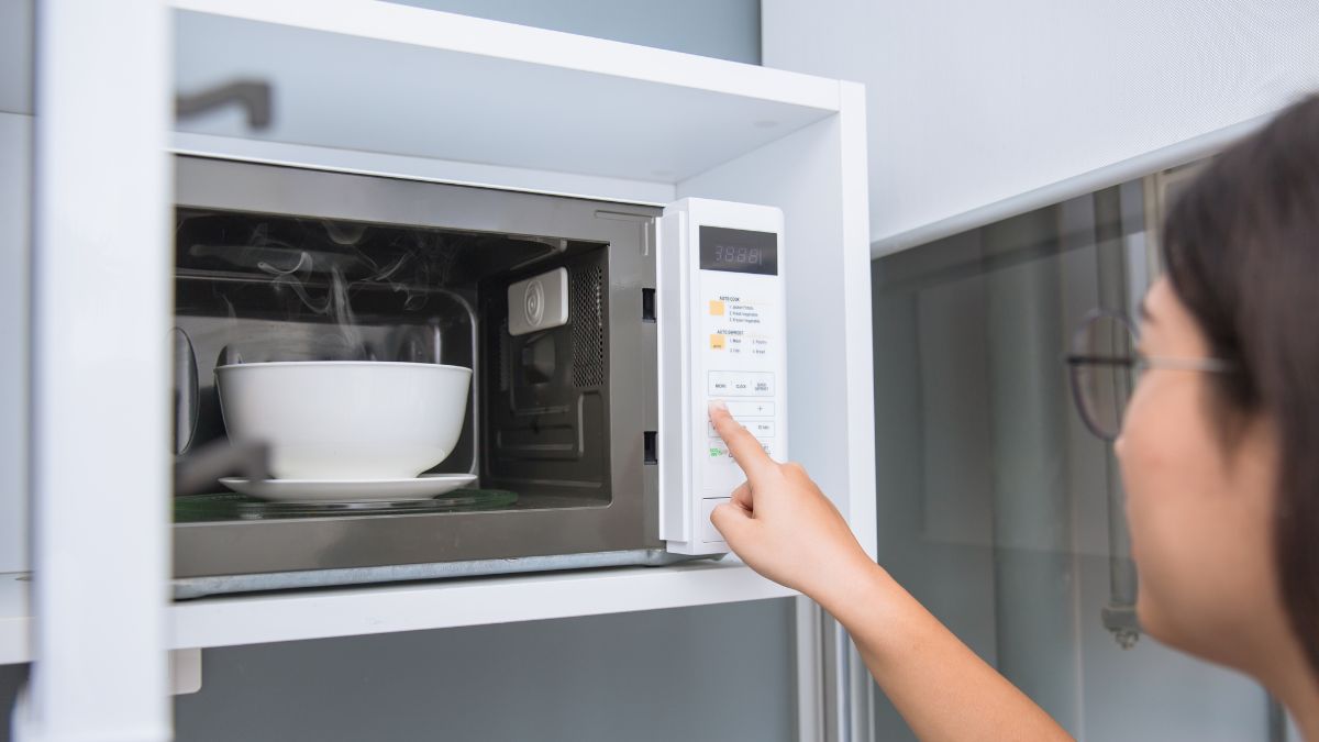A Woman Putting a Bowl into the Microwave