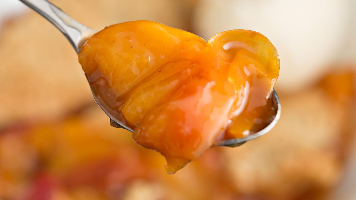 A closeup of a spoonful of peach cobbler srrved with warm syrup (sherbert)