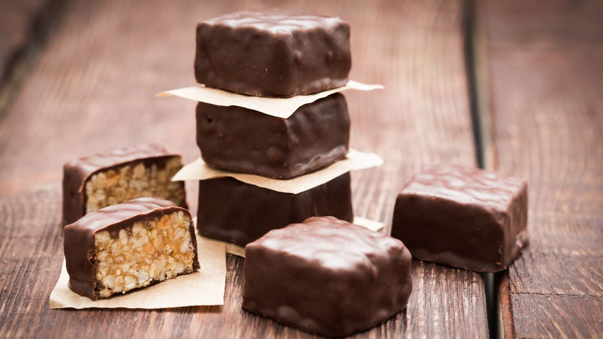 Chocolate-covered peanut brittle pieces wrapped in wax paper