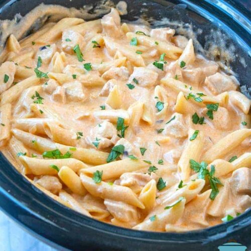 Crock Pot Buffalo Chicken Pasta fully cooked in an oval slow cooker topped with chopped parsley