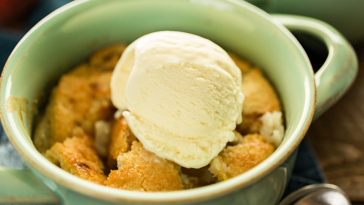 Dryed Out Peach Cobbler Served With a Scoop of Vanilla Ice Cream in a green earthenware dish