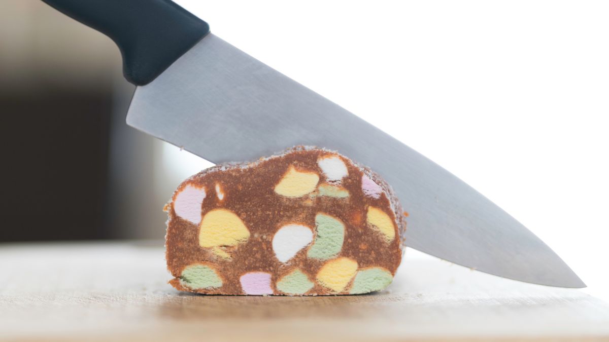 Side view close up of large kitchen knife cutting a slice of lolly cake