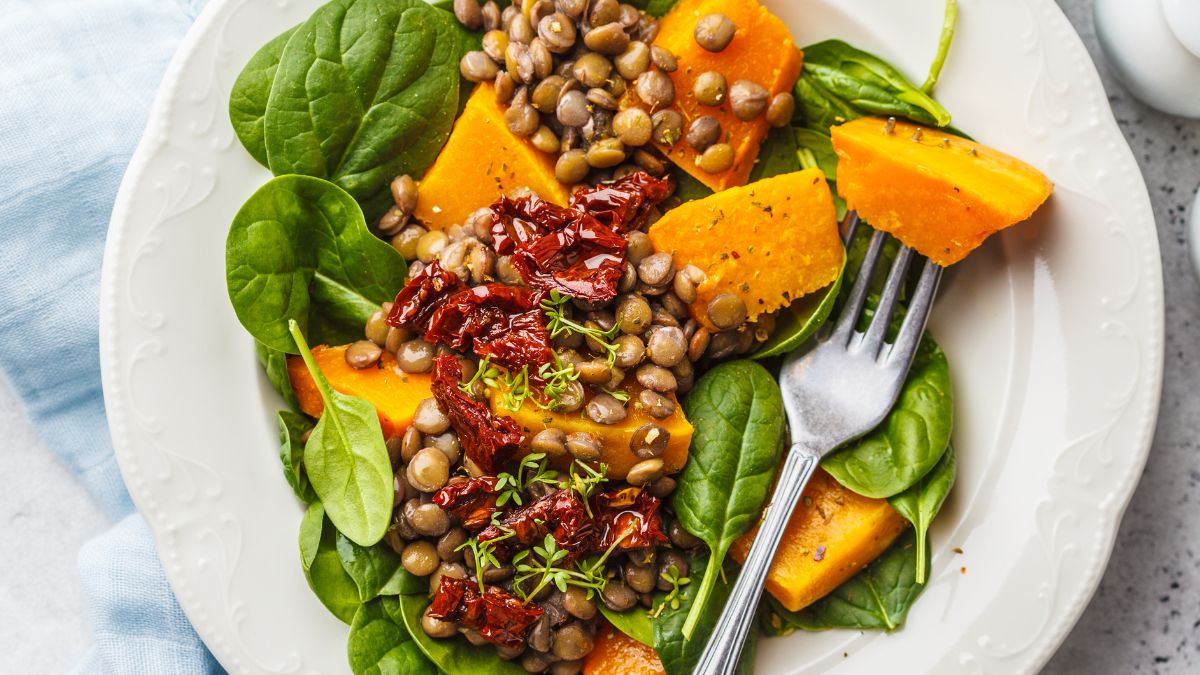 Vegetable Salad With Spinach, Pumpkin, Dried Tomatoes, and Lentils Instead Of Corn On A White Plate