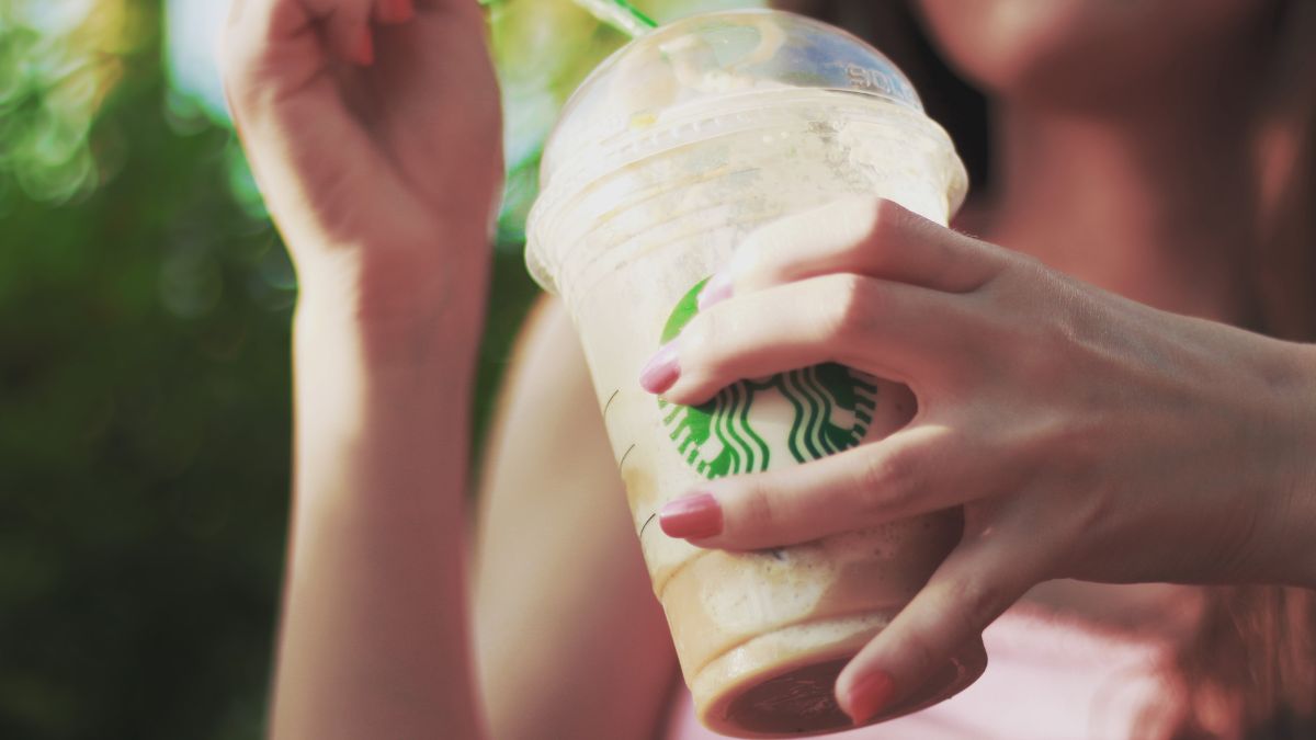 a woman holding a plastic Starbucks cup closeup