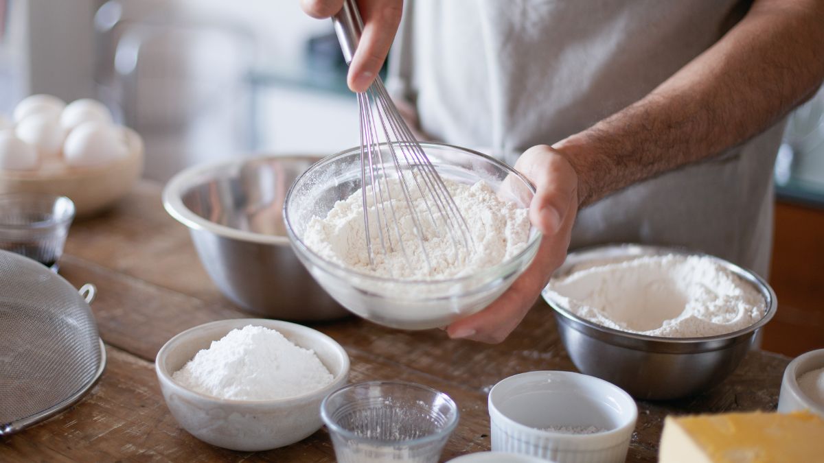 a person baking with flour, surrounded by bowls with different ingredients