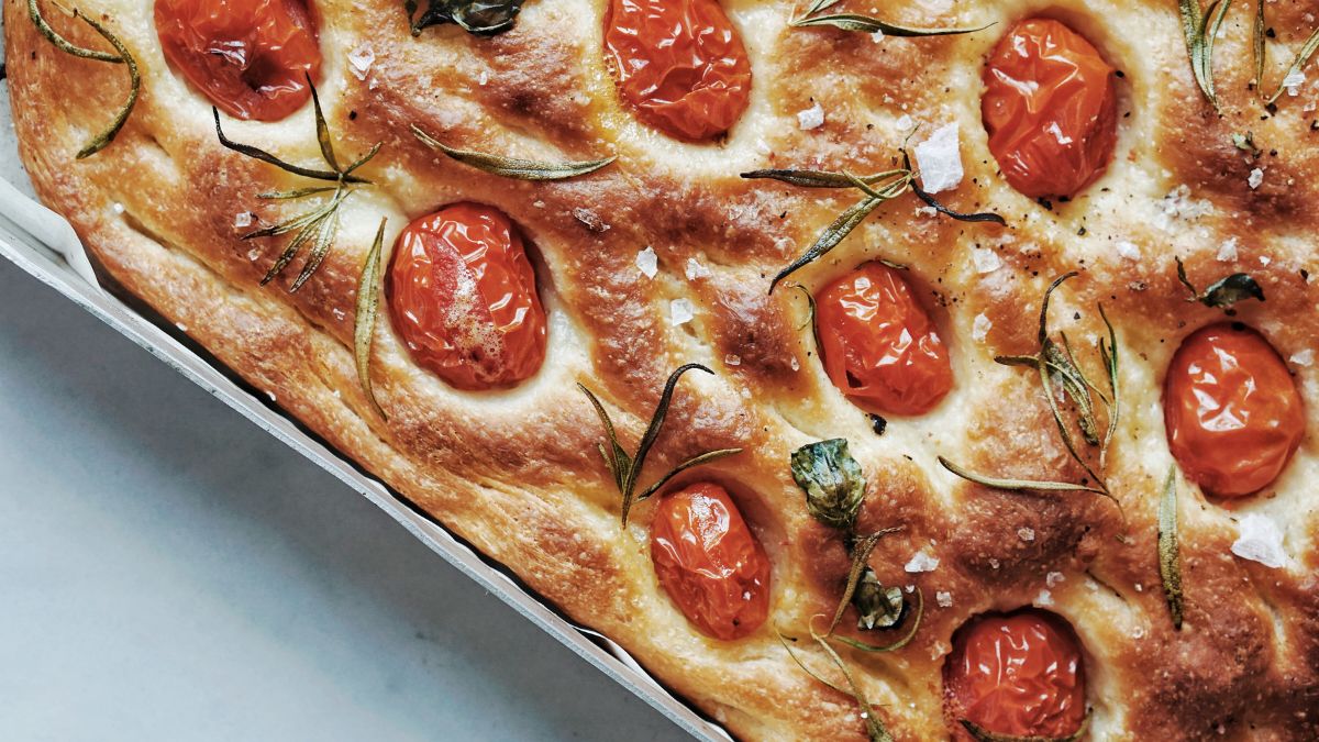foccacia bread freshly baked with cherry tomatoes, herbs, and kosher salt