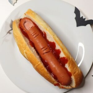 HALLOWEEN FINGER FOOD. Hot dogs that look like fingers in a hot dog buns on ketchup.