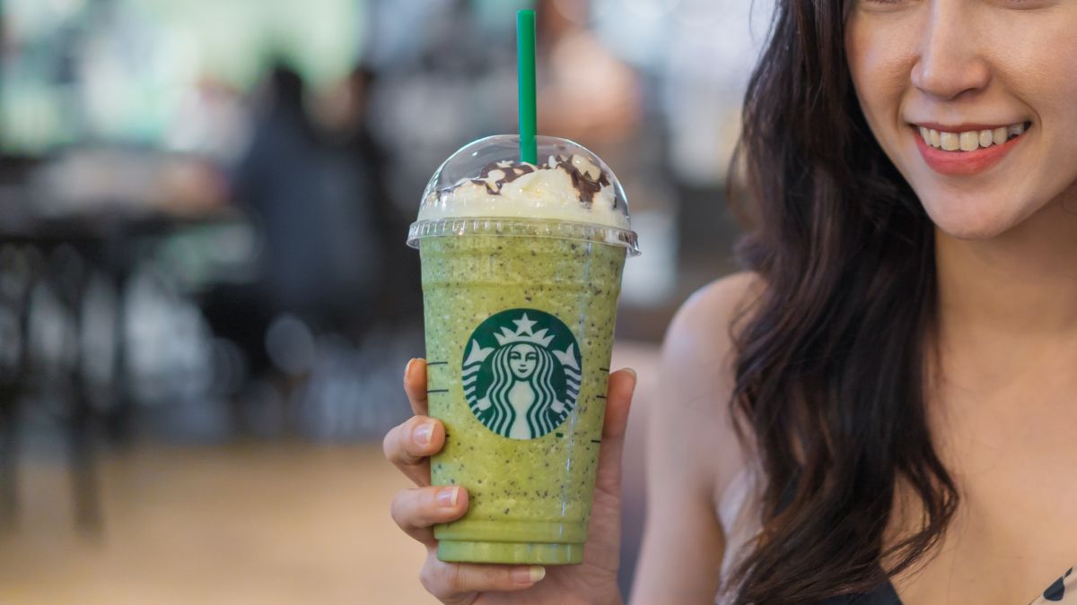 a woman holding a starbucks green tea frappe with vanilla syrup and whipped cream on a Starbucks location